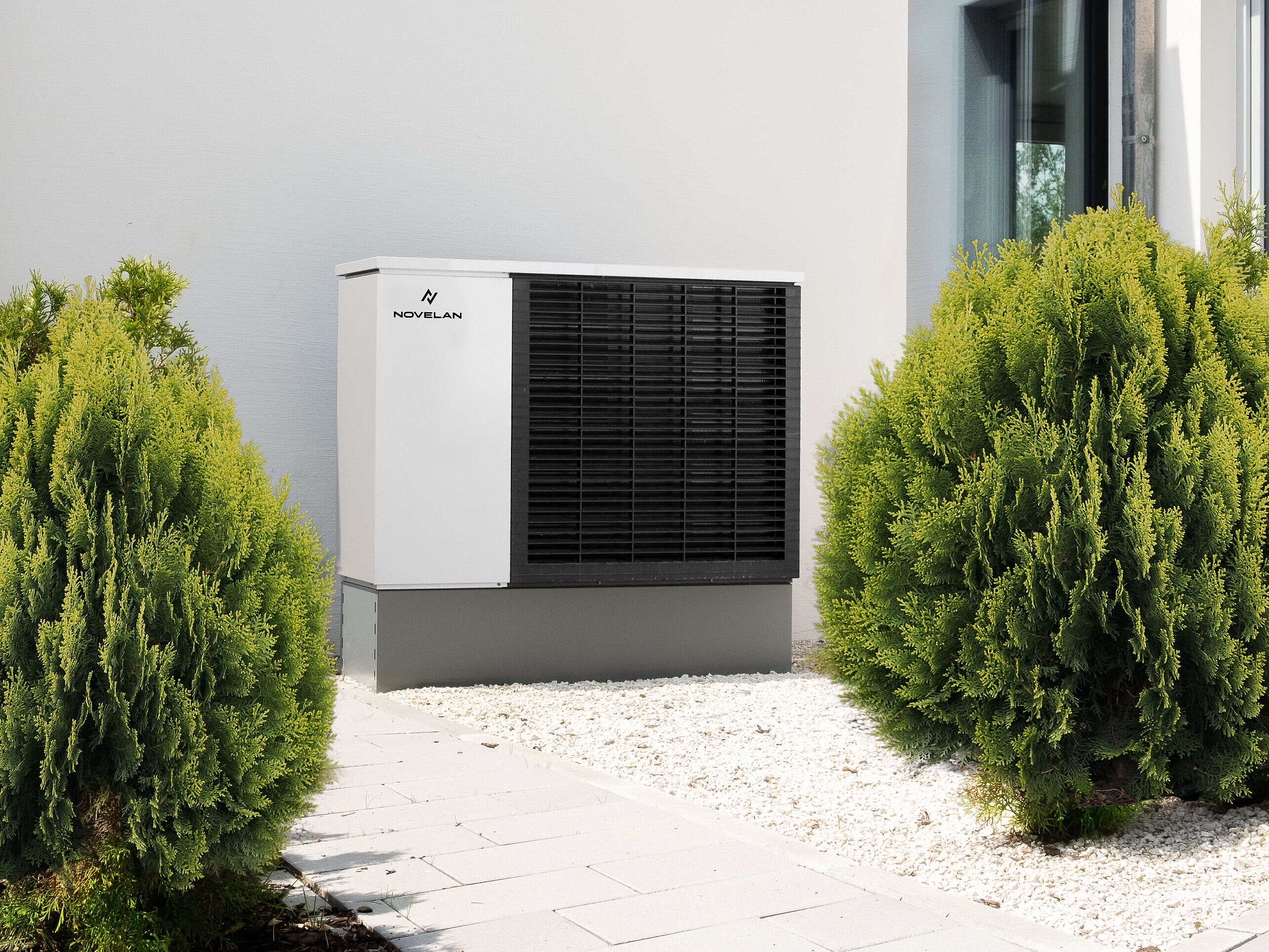 Wärmepumpe steht an einer weißen Hausfassade